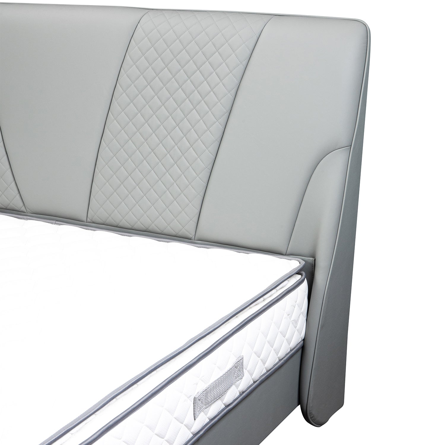Gray leather upholstered bed frame headboard with quilted detailing and corner of mattress with white cover