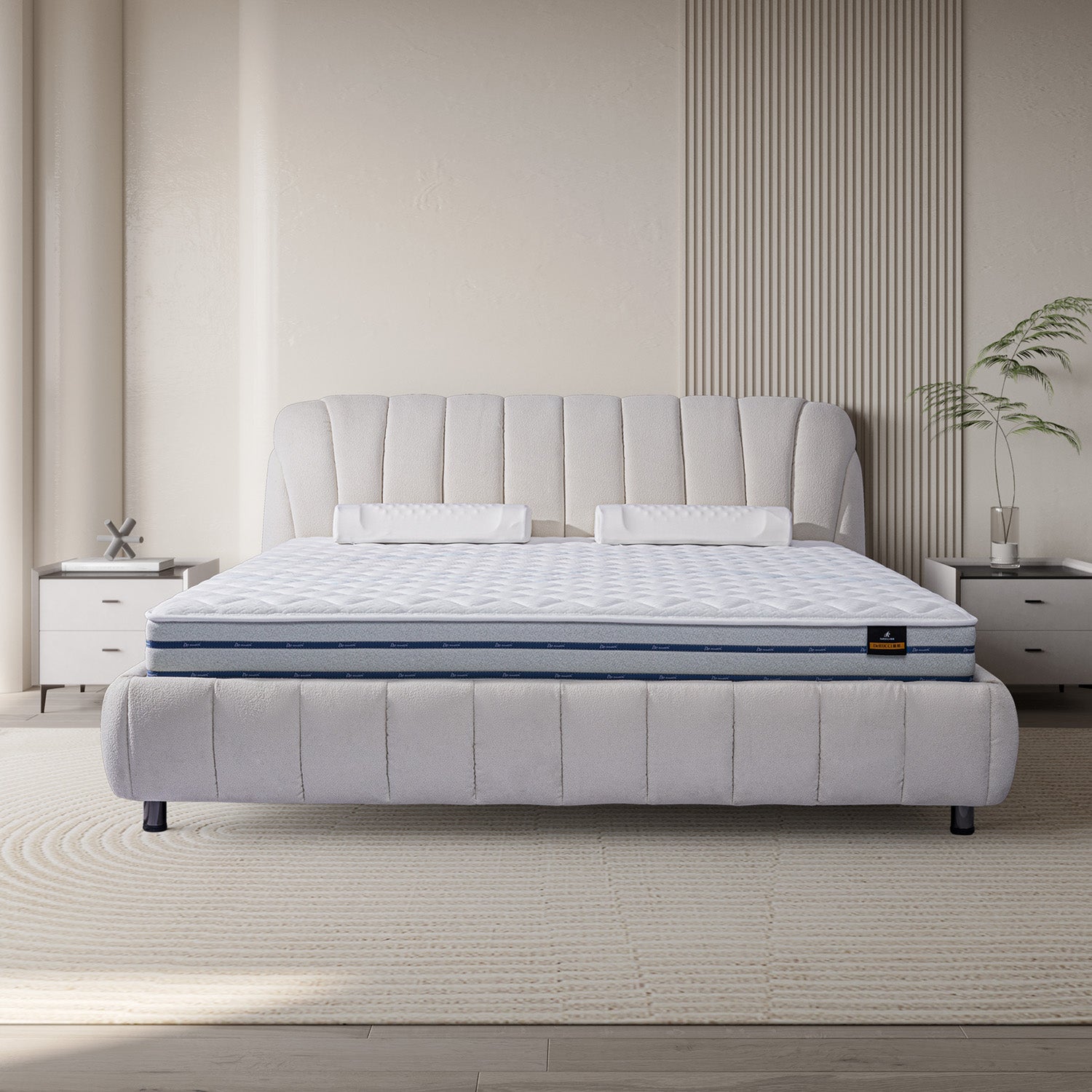 DeRUCCI BOC1-015 white fabric bed frame with padded headboard and quilted mattress in a modern bedroom with white nightstands, decorative plants, and a light, textured rug.