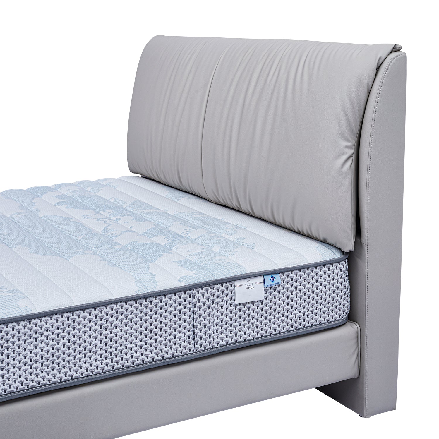 Close-up view of DeRUCCI's bed frame BOC1 - 012 with grey upholstered headboard and quilted grey and white mattress.