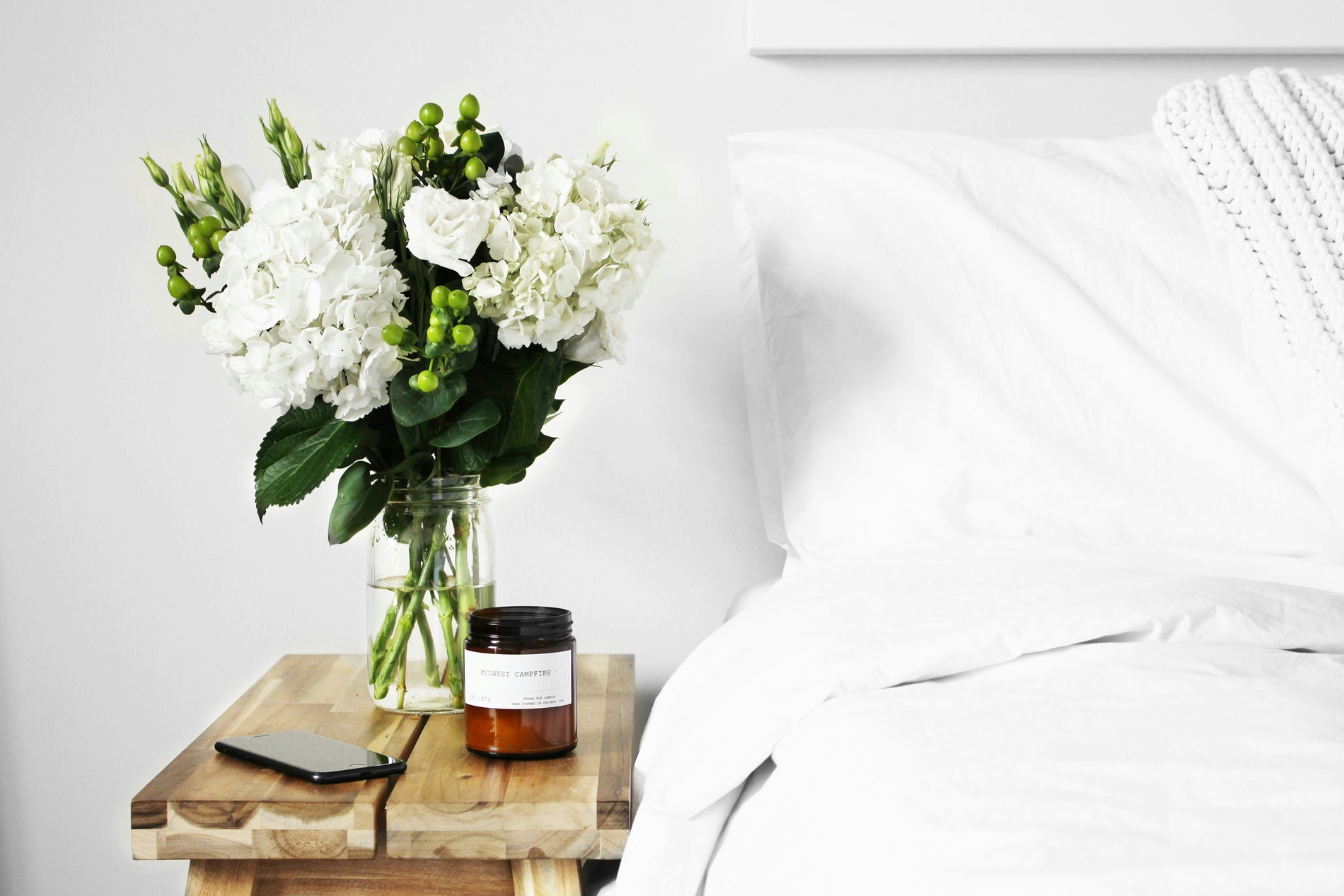 A neatly made bed with crisp white sheets and a cozy knit throw, inviting restful sleep