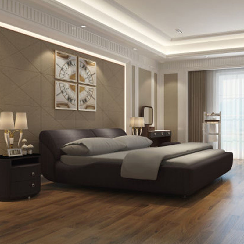 Modern black leather bed frame with soft gray cushions and bedding in an elegant bedroom with wooden flooring and clock-themed art on the wall.