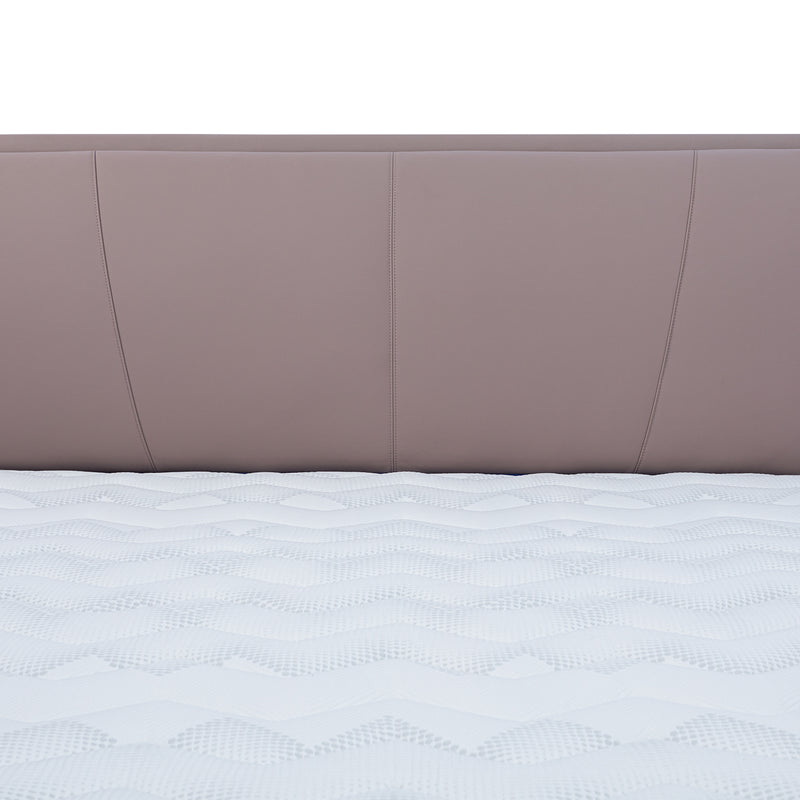 Close-up view of light brown leather bed frame headboard with vertical stitching and white patterned mattress from DeRUCCI.